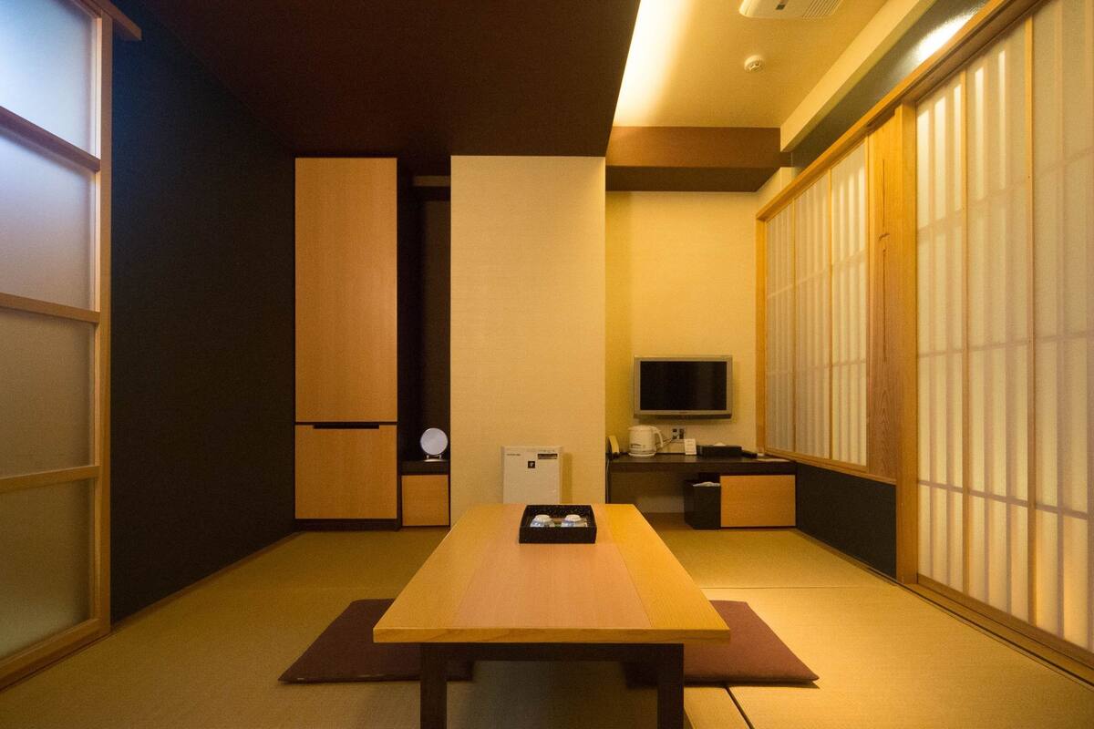 A traditional Japanese room with tatami flooring, a low table, a television, and sliding doors.
