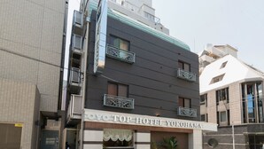 Un hotel con fachada moderna, que presenta un cartel llamativo con el nombre "TOYO TOP HOTEL YOKOHAMA".