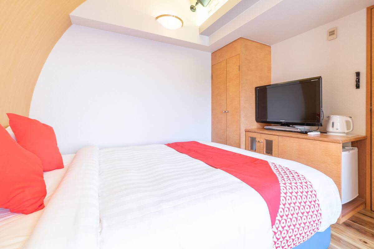 Une chambre d’hôtel équipée d’un lit, d’une télévision, d’une machine à café et d’une armoire.