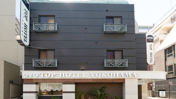 Un hotel con fachada moderna, balcones con barandillas decorativas y un letrero que indica que es el Top Hotel Yokohama.