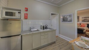 Een compacte keuken met een magnetron, spoelbak en een koelkast. Er hangen twee branddeken bordjes aan de muur.