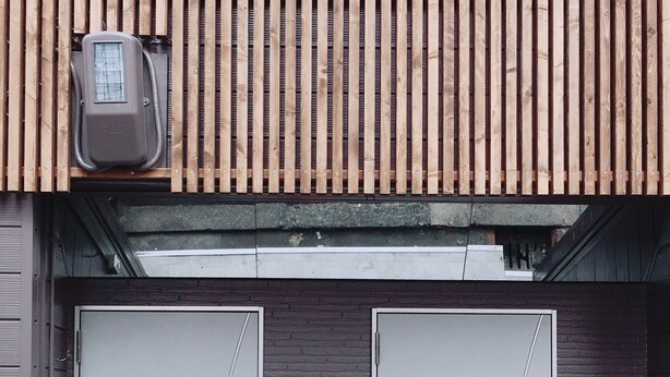 A building with two grey garage doors, a small red mailbox, and a utility box on the roof. - Guesthouse SAYURI 2 (Osaka)