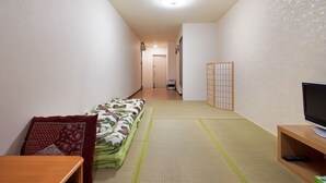 A narrow hallway with a futon bed, a television on a wooden stand, and a tatami mat floor. - Guesthouse SAYURI 2 (Osaka)
