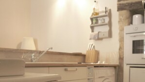 Eine Küche mit Waschmaschine, Spüle und einer Arbeitsplatte, auf der eine Lampe und ein Schneidebrett stehen.