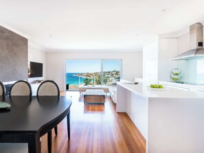 A modern apartment with a dining area, kitchen, and a balcony with a city view.