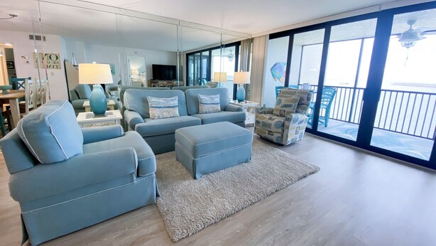 A modern living room with a large sectional sofa, a small armchair, and a flat-screen TV. - Sanibel Harbour Resort Harbour Tower 714:     Coastal condo with a festive lanai (Fort Myers)