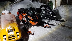 A snowmobile and a sled parked on a snow-covered ground. - Executive Suites (Chapleau)