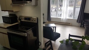Una cocina funcional con microondas, estufa y una pequeña mesa de comedor con una silla.