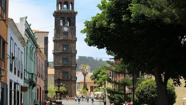 A historic tower with a clock, surrounded by buildings and a tree-lined street. - APARTMENT - San Cristóbal de La Laguna (San Cristóbal de La Laguna)