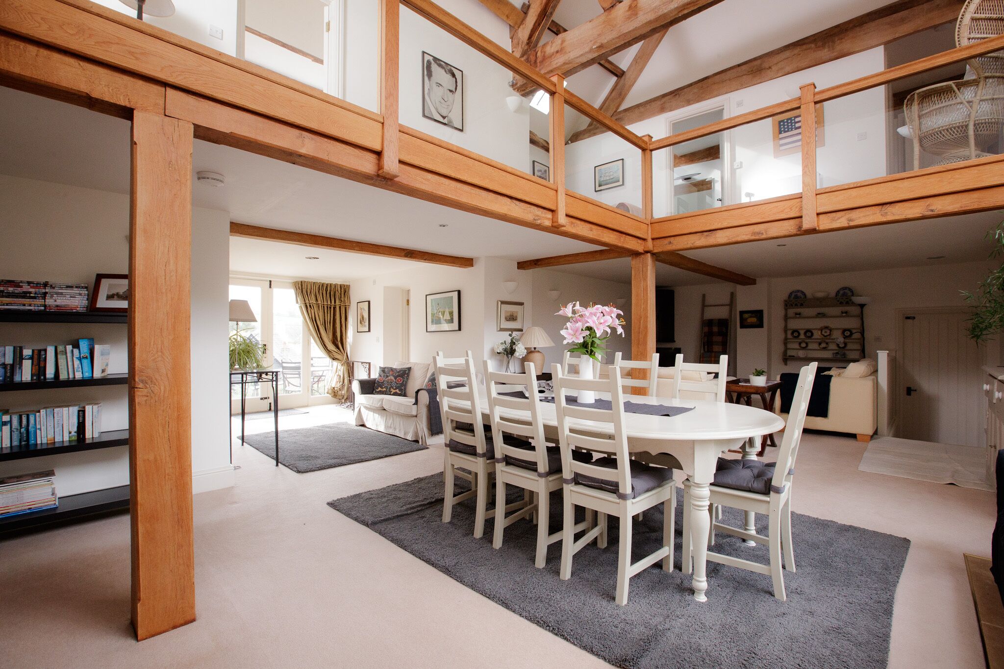 A spacious dining area with a wooden ceiling, a round table, and white chairs.