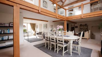 A spacious dining area with a wooden ceiling, a round table, and white chairs.