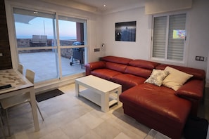 A living room with a red leather sofa, a white coffee table, and a dining area with a table and chairs.