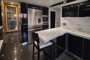 A modern kitchen with a white countertop, stainless steel appliances, and black cabinetry.
