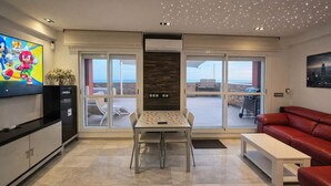 A modern living room with a television, a dining table, and a red leather sofa. - Spectacular Penthouse, authentic 1st line beach, 70 m2 terrace  (Rota)