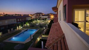 A residential area with a swimming pool, well-lit pathways, and houses with balconies. - Spectacular Penthouse, authentic 1st line beach, 70 m2 terrace  (Rota)