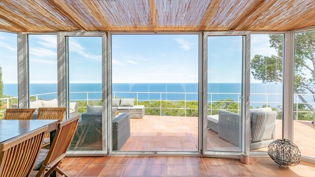 Un balcon spacieux offrant une vue dégagée sur la mer, aménagé avec des fauteuils et une table en osier.