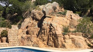Une piscine bordée de rochers, avec des marches en pierre menant à l’eau.