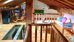 Een rustiek houten interieur met een stenen muur, een houten schommel, een houten bank en een glazen uitkijkpunt.
