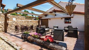 Una terrazza esterna con pareti in pietra, travi di legno e mobili da giardino.