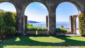 Ein steinerer Torbogen mit Blick auf das Meer und ferne Berge.