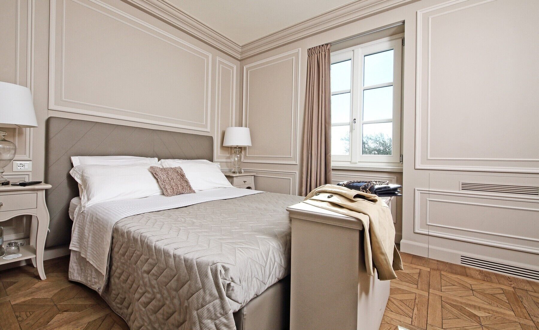 Une chambre d’hôtel avec un lit, une table de chevet, une lampe et un porte-manteau sur lequel est accrochée une veste.