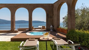 Ein Poolbereich mit Whirlpool, Liegestühlen und Seeblick.