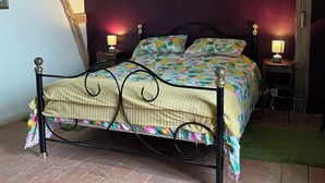 Un letto con una coperta a fiori, due abat-jour e un soffitto in legno.