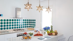 A modern kitchen with a white island, star-patterned backsplash, and hanging star-shaped lights. - Eden House Positano, Amazing Seeview Apartment Car Parking shared pool (Positano)