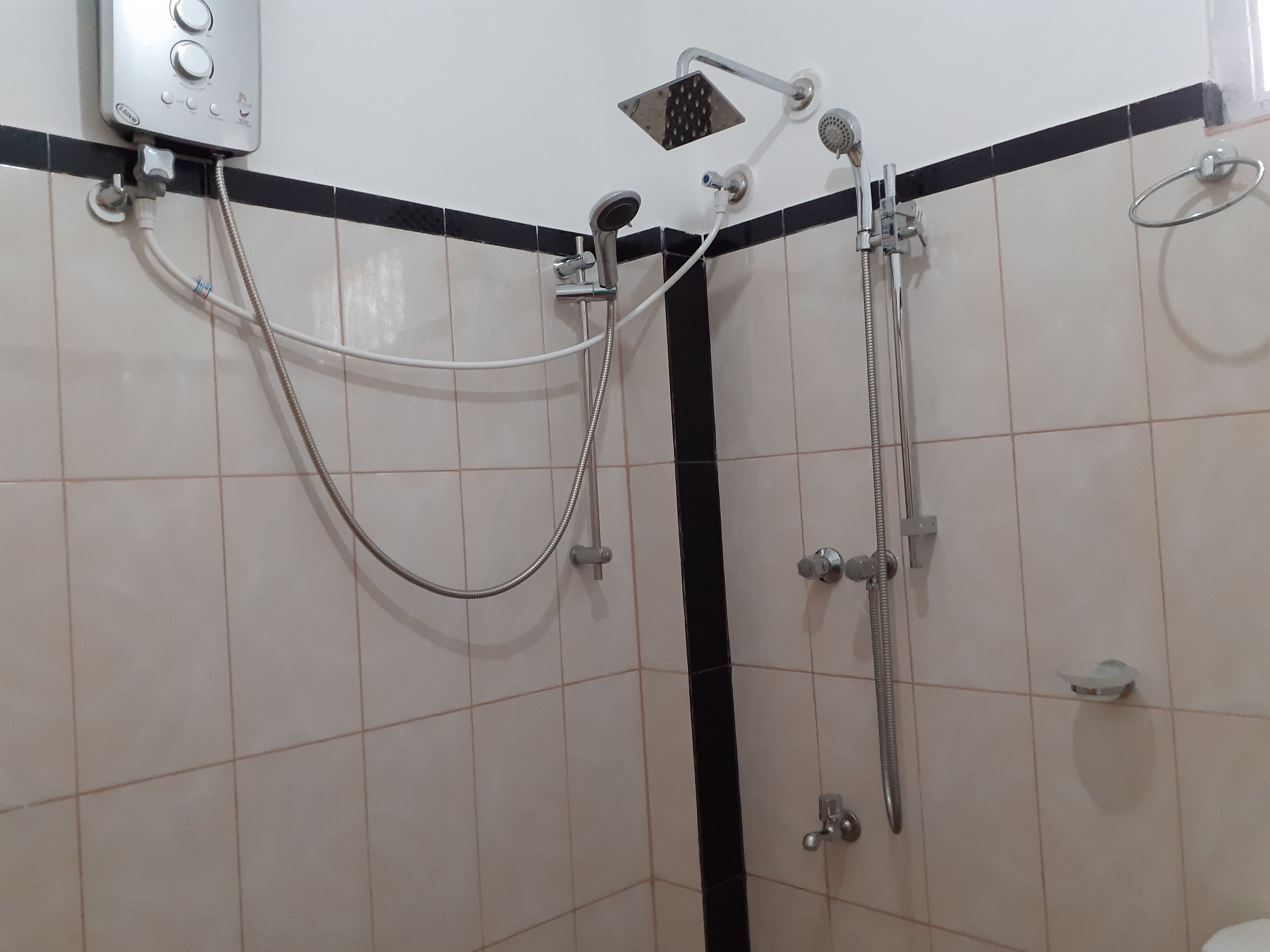 A bathroom with a shower, a handheld showerhead, and a wall-mounted control panel.