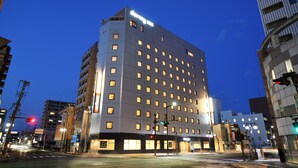 Un hotel de varios pisos con diseño moderno, con numerosas ventanas y una entrada destacada.