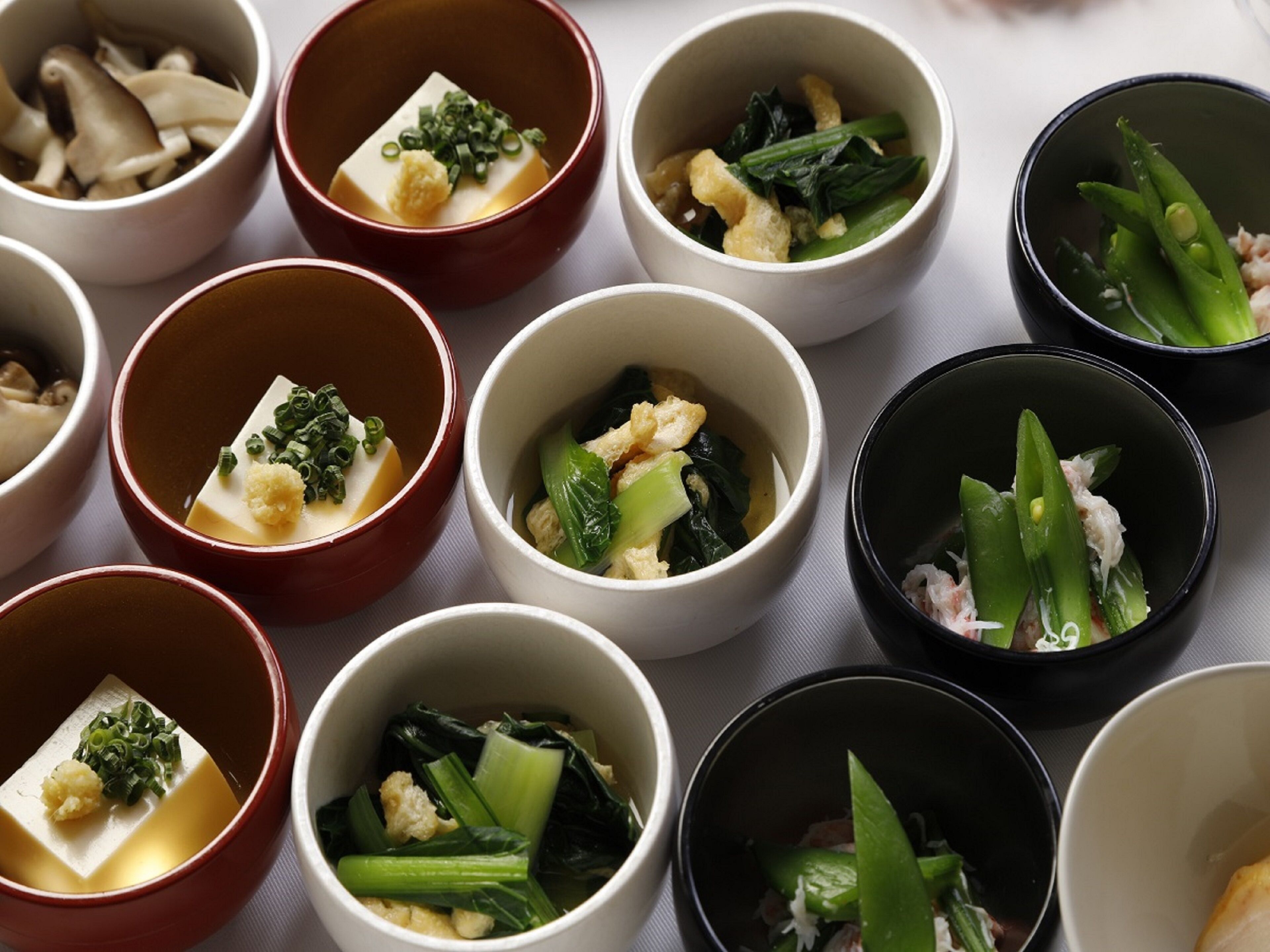 Una variedad de recipientes pequeños con distintos tipos de comida, dispuestos sobre una mesa.