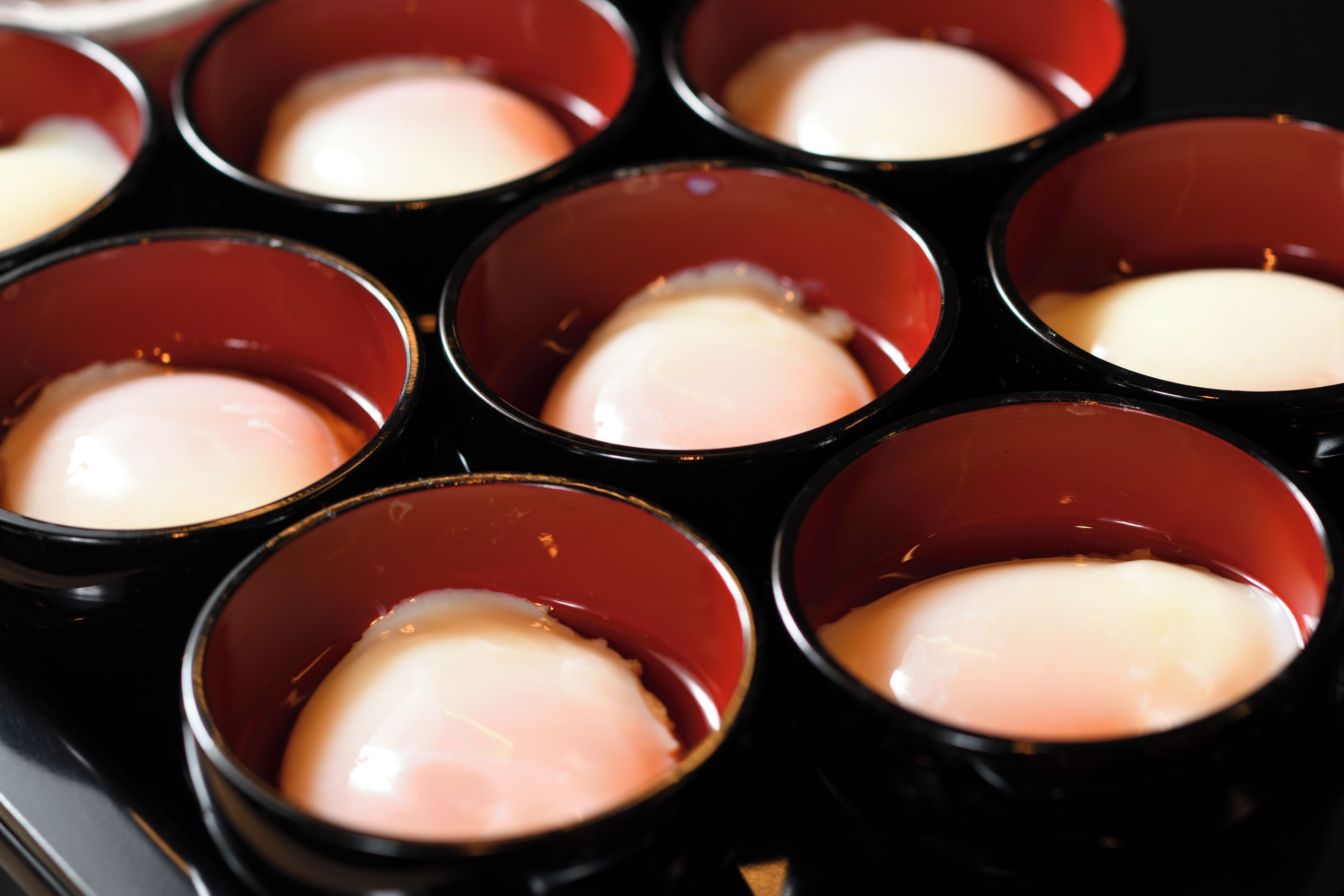 Une vue rapprochée de plusieurs gobelets rouges contenant une substance blanche, qui pourrait être un dessert ou une boisson.