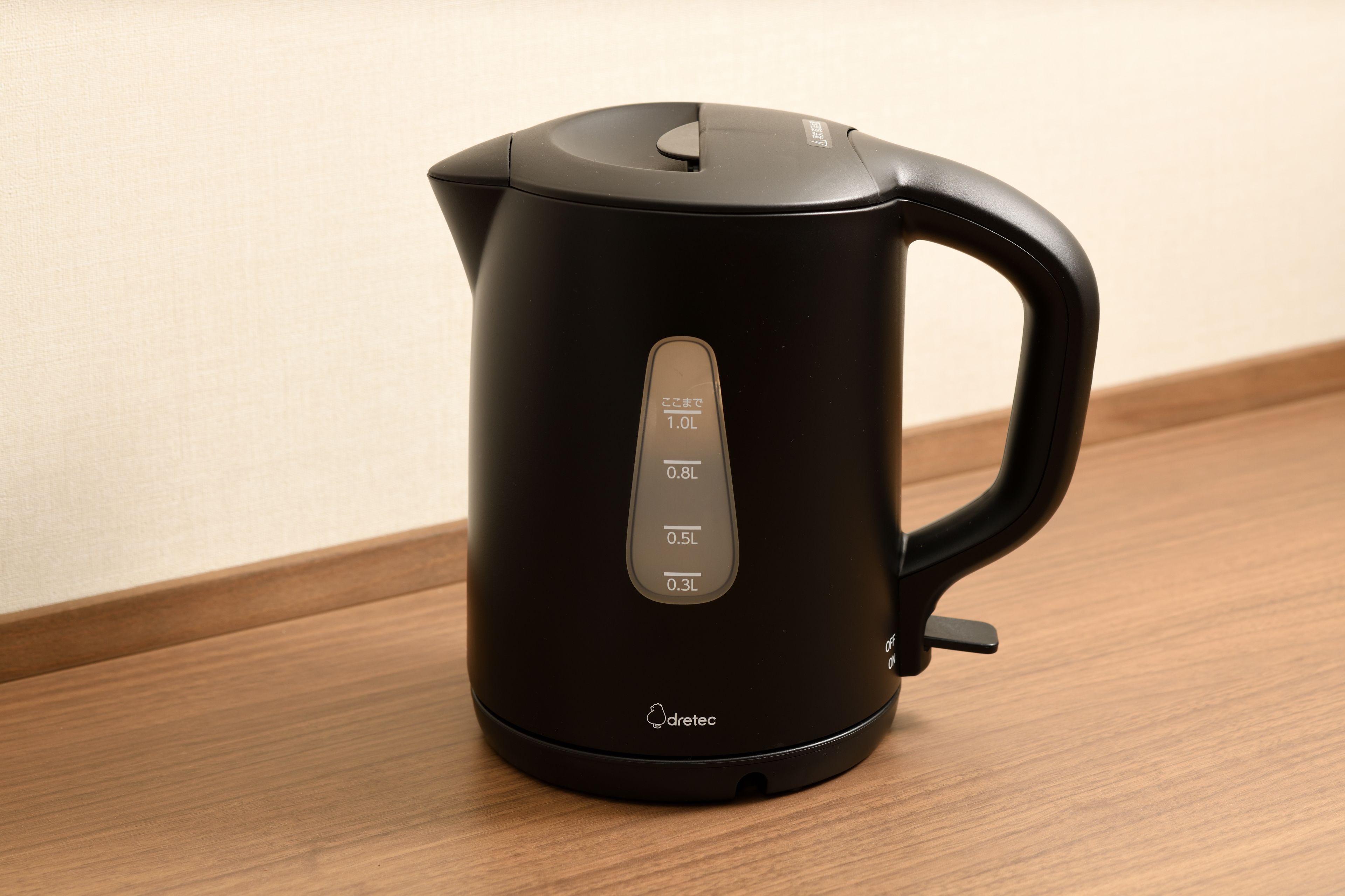 A black electric kettle with a digital display on a wooden surface.