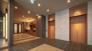 Un moderno vestíbulo de hotel con un mostrador de recepción y dos ascensores.