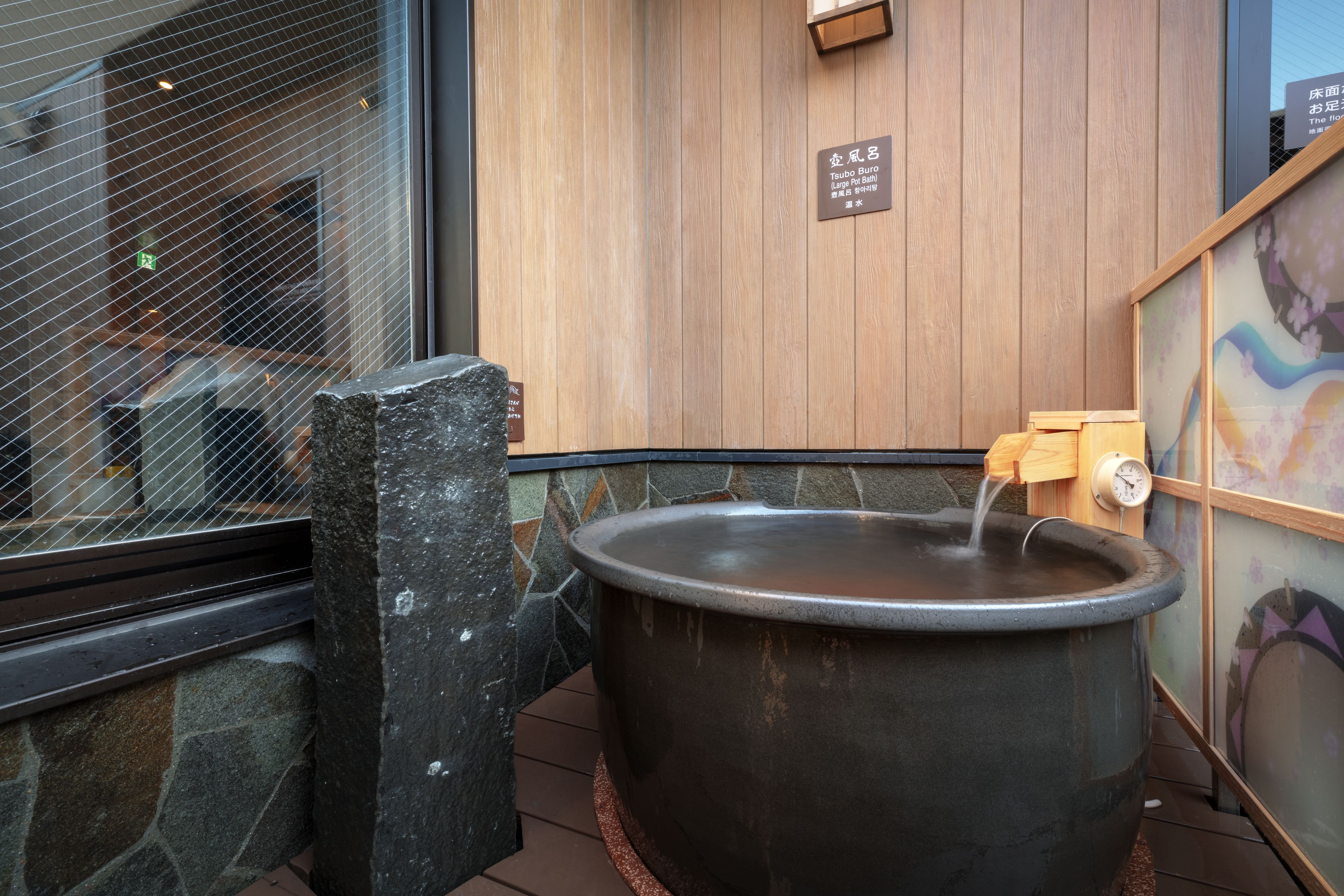 Een stenen muur met een ruime hottub en een houten bord.