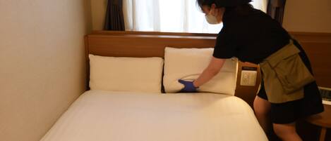 Una habitación de hotel con una cama bien hecha, un cabecero de madera y una ventana con cortinas.