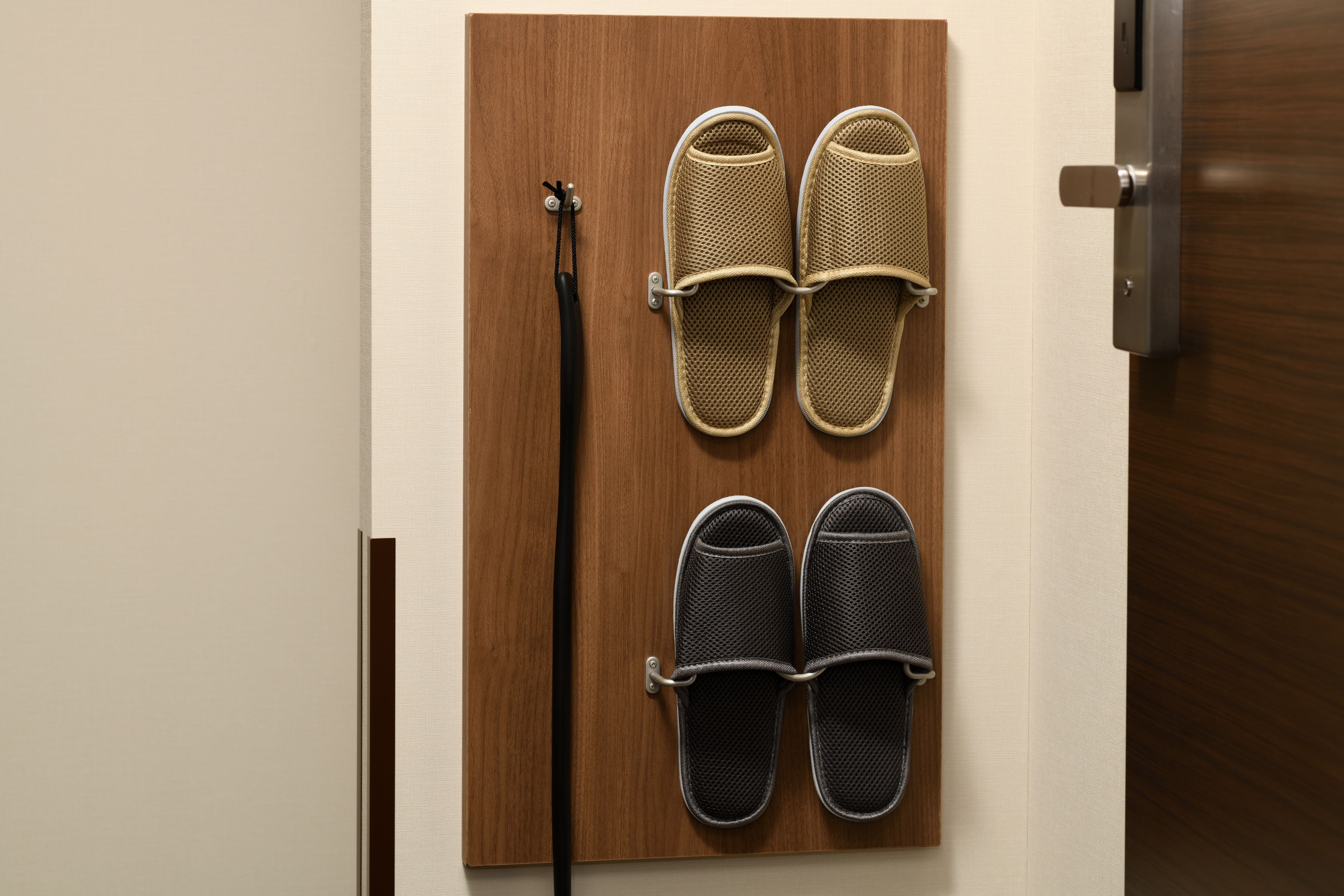 A wooden door with a metal shoe rack holding two pairs of slippers.