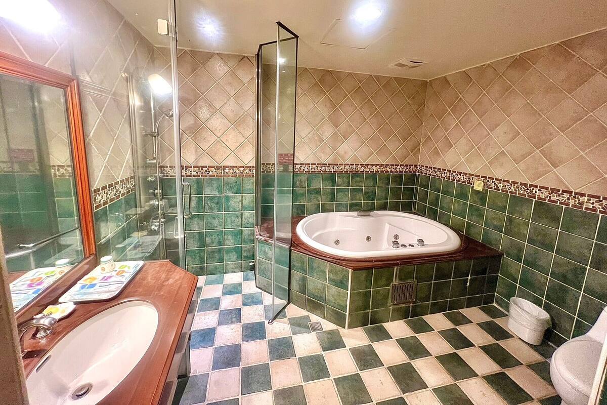 Ein Badezimmer mit einer gläsernen Duschkabine, einer freistehenden Badewanne und einem Schachbrettfußboden.