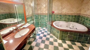 Un baño con dos lavamanos, ducha envuelta en vidrio y bañera independiente.