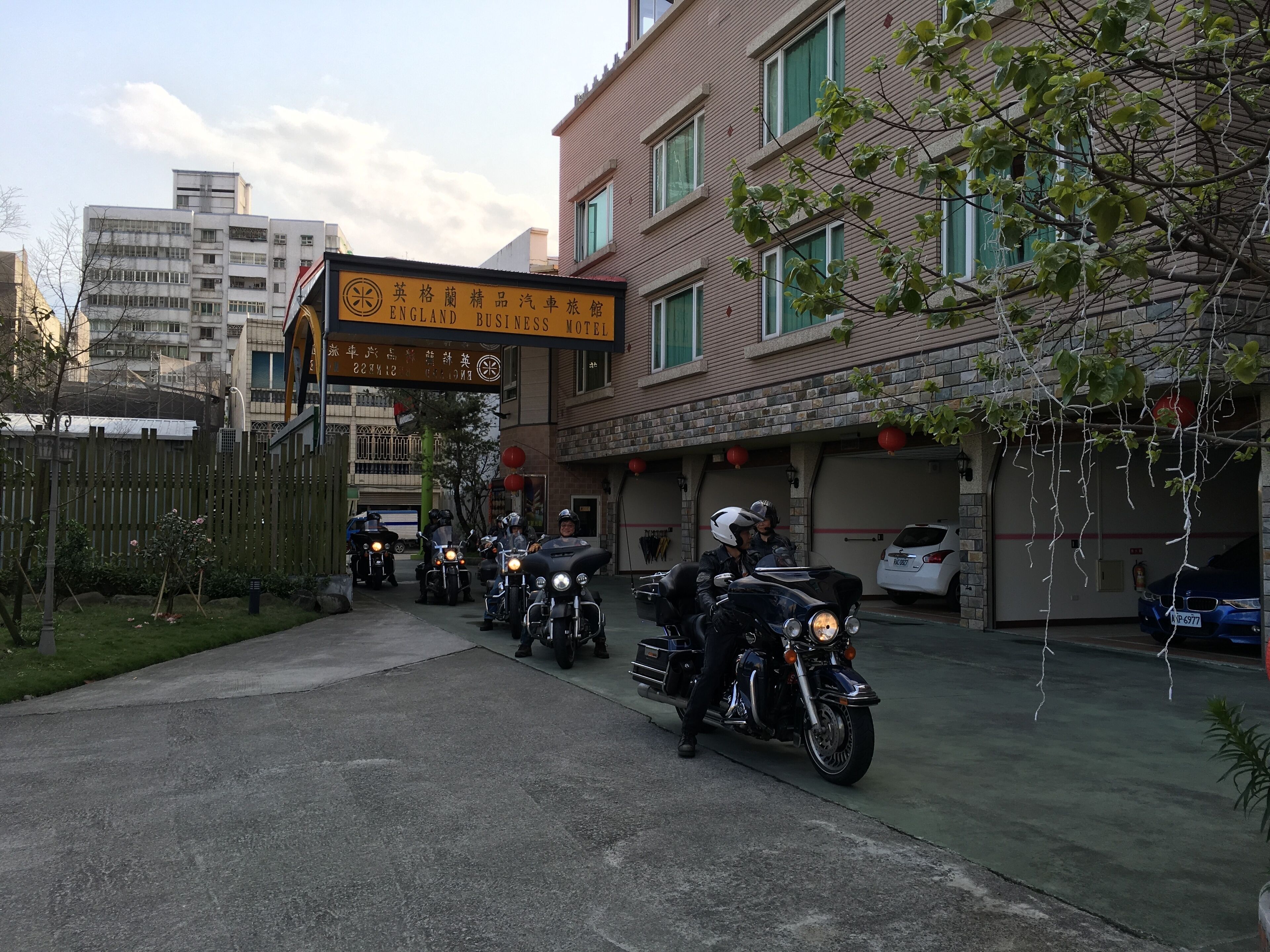 A business motel with a signboard, a brick building, and parked motorcycles.
