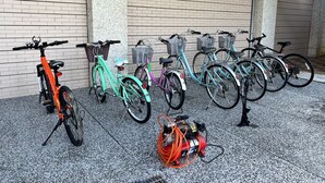 Varias bicicletas están estacionadas frente a un edificio con una pared moteada y un suelo de concreto.