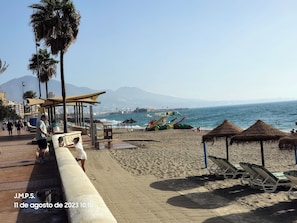 Ein Strand mit Palmen, einem Rettungsturm und Liegestühlen.