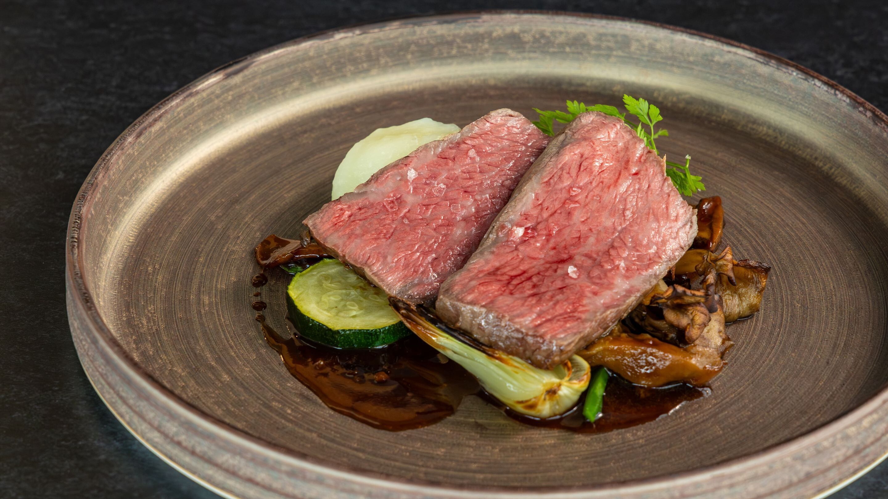 Une assiette contenant de la viande en tranches, des légumes et une sauce.