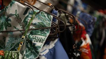 Un portant à vêtements sur lequel sont disposés divers articles, notamment un tissu à motifs verts et blancs et un vêtement bleu.