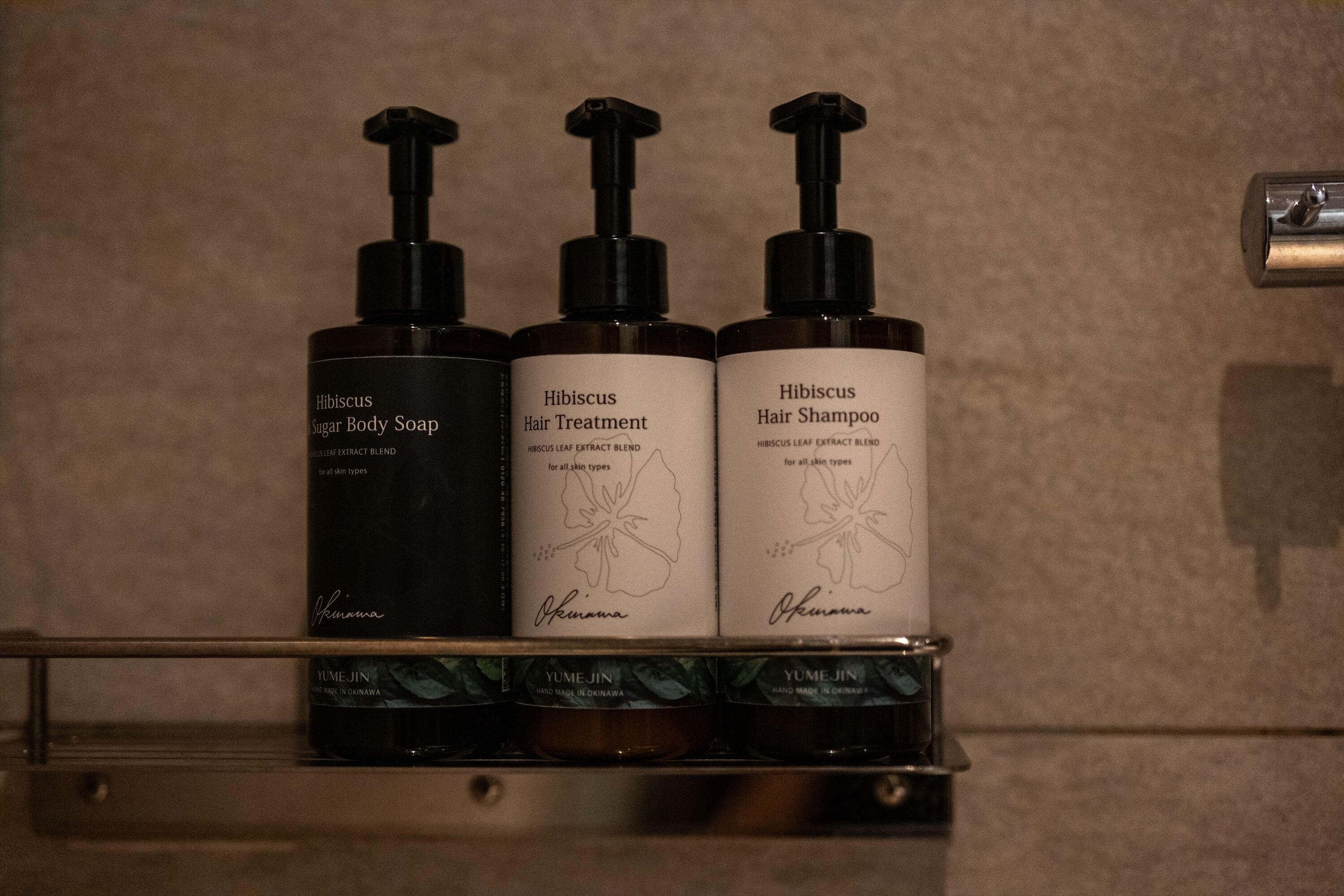 Tres botellas de productos de Hibiscus en una estantería.