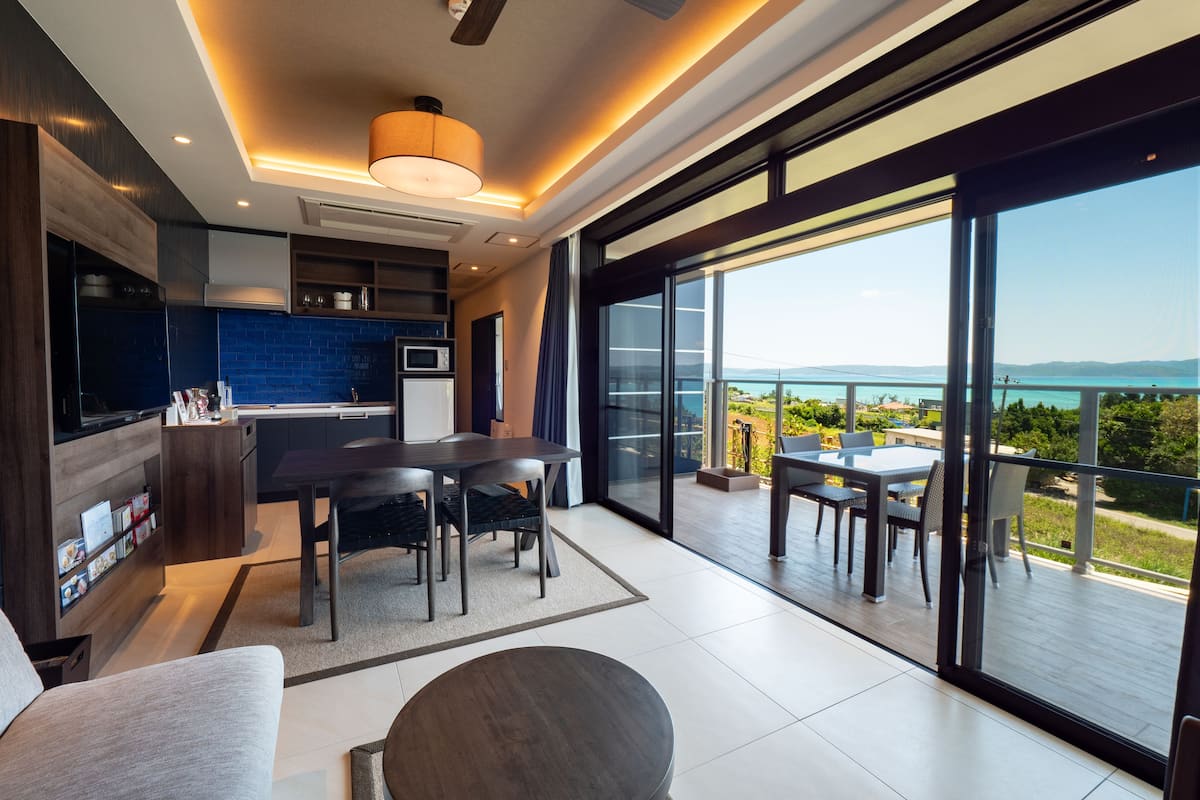 A modern kitchen with a dining area and a balcony with a view.