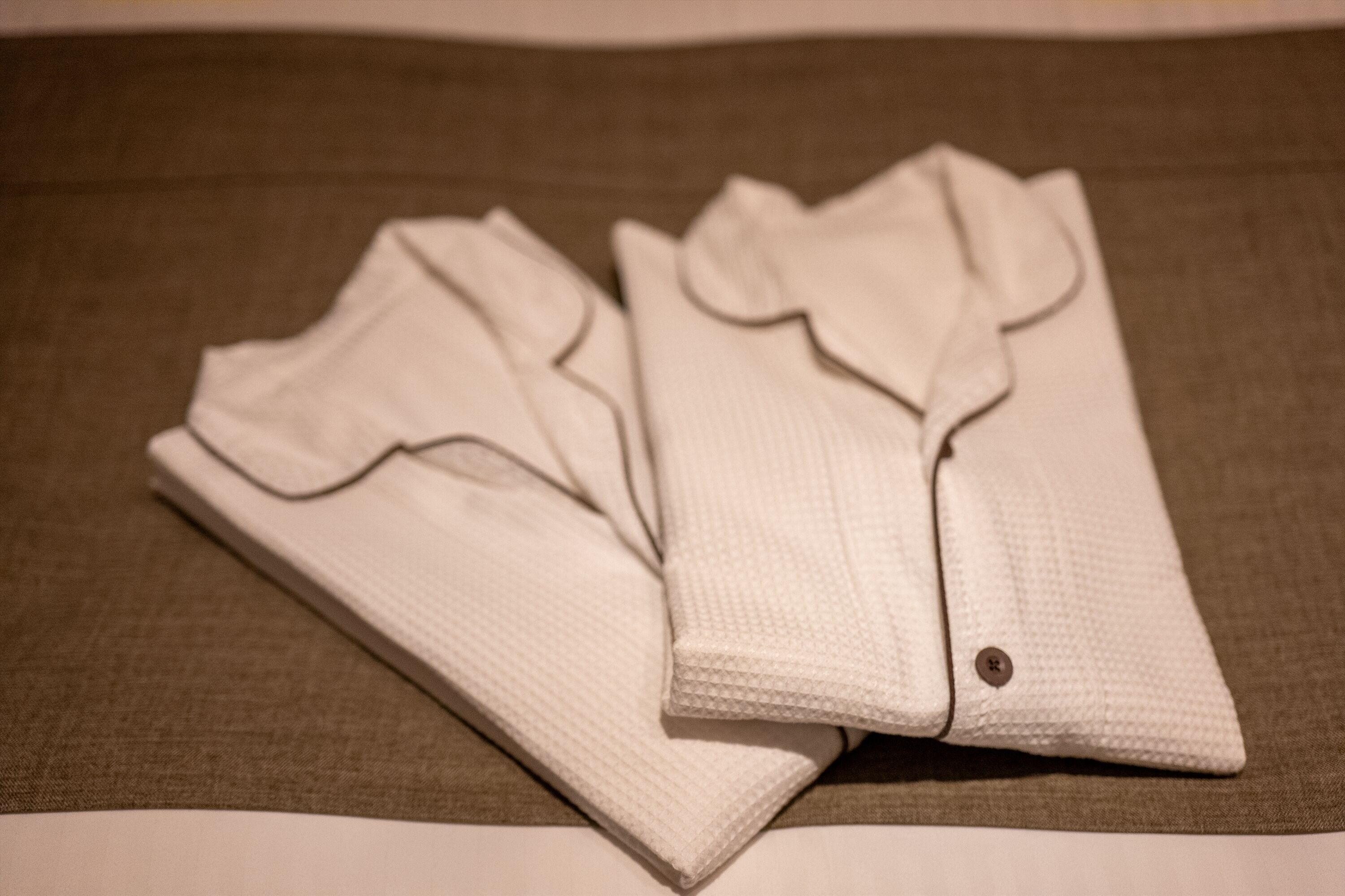 A neatly folded white shirt on a textured fabric surface.