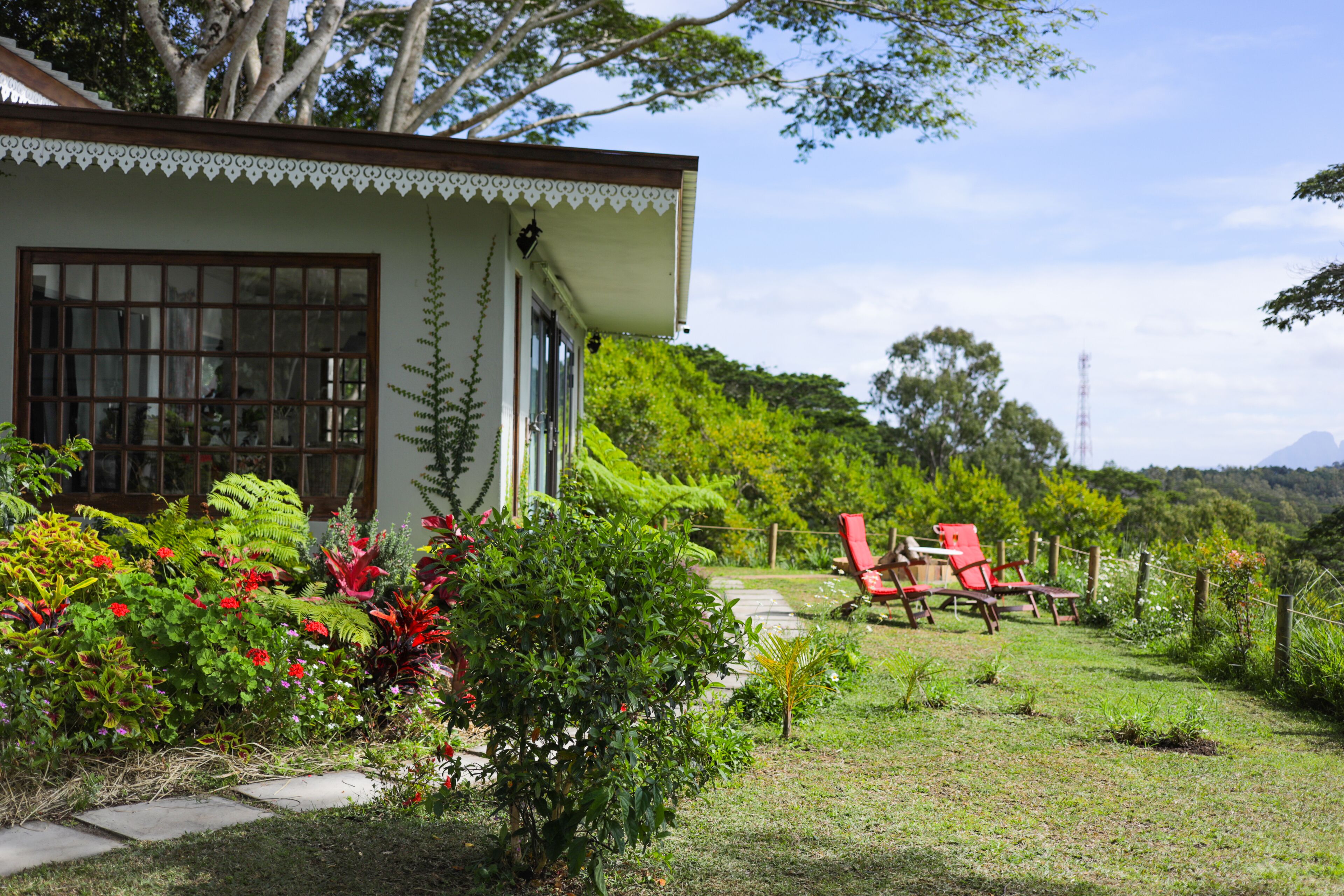 A house with a garden, a pathway, and red chairs.