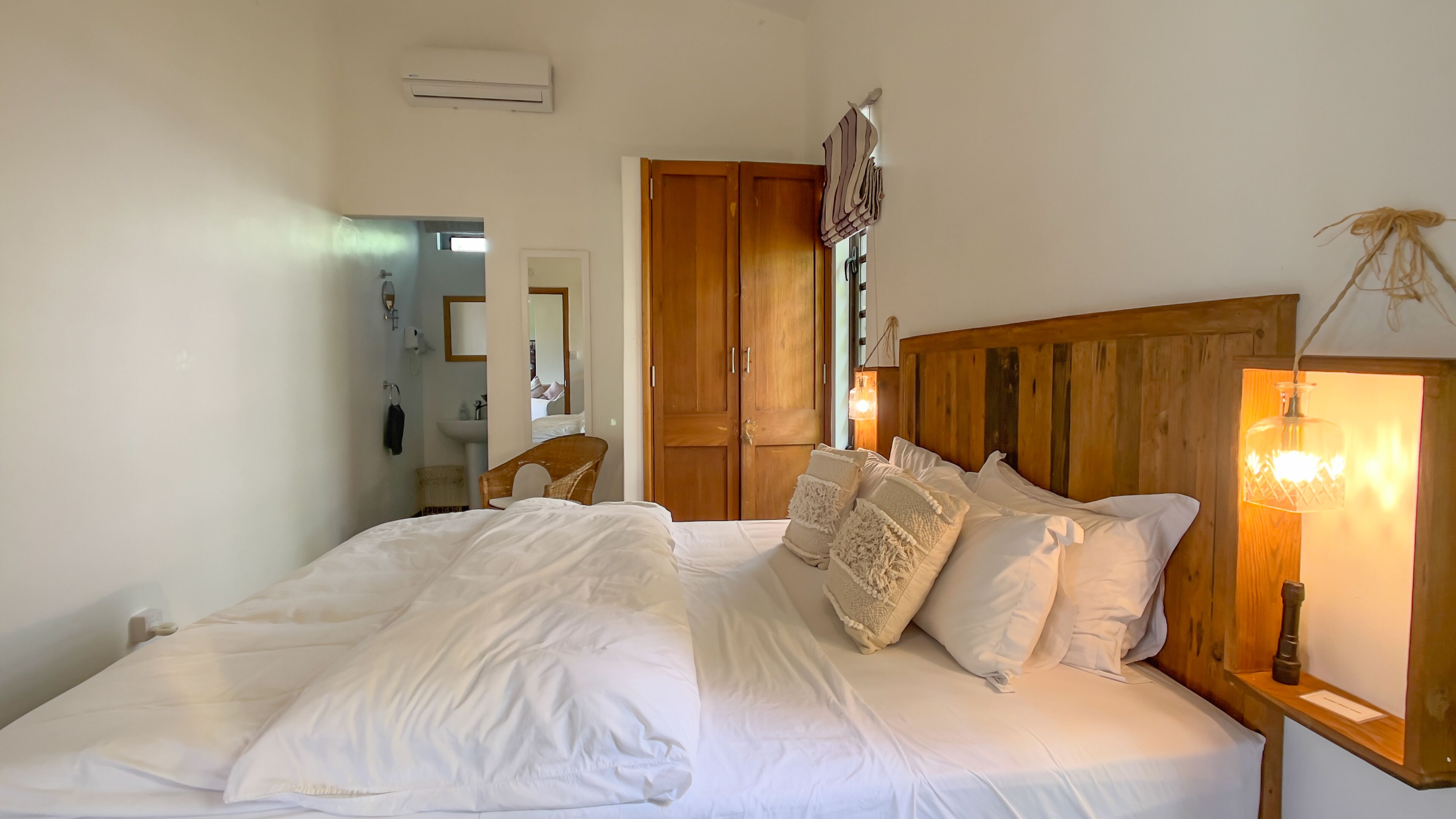 Ein Schlafzimmer mit einem großen Bett, einem Holz-Kopfteil, Nachttischlampen und einem Kleiderschrank.