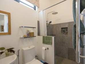 A bathroom with a toilet, sink, shower, and a towel rack. - Green Cottage Chamarel (Chamarel)